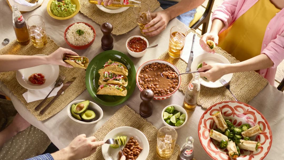 Overhead view of friends sharing a table of dishes, hands reaching in, no faces shown