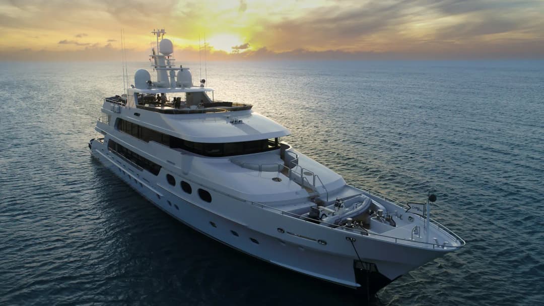 A large white superyacht on open water in warm evening light.