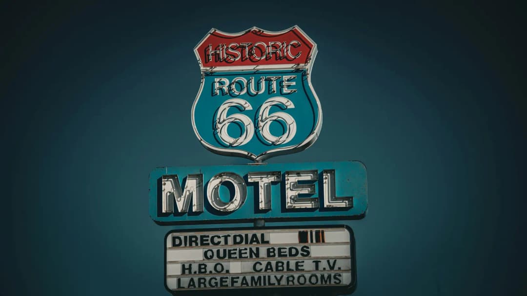 Historic Route 66 motel sign with the shield emblem on a dark teal background