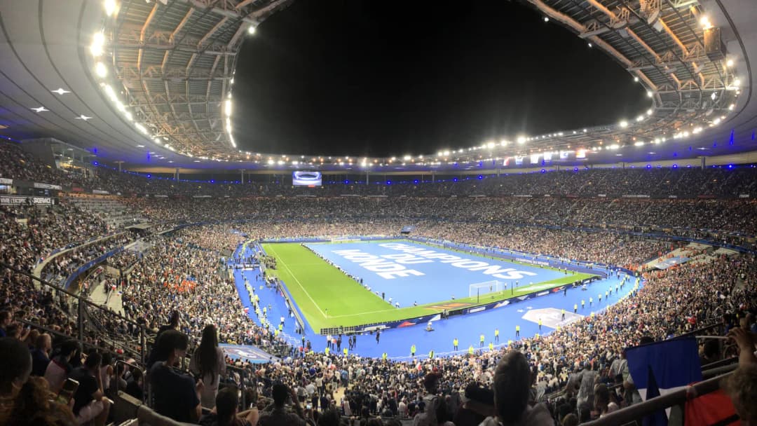 Stade de France at night, packed stands around a lit pitch during a match