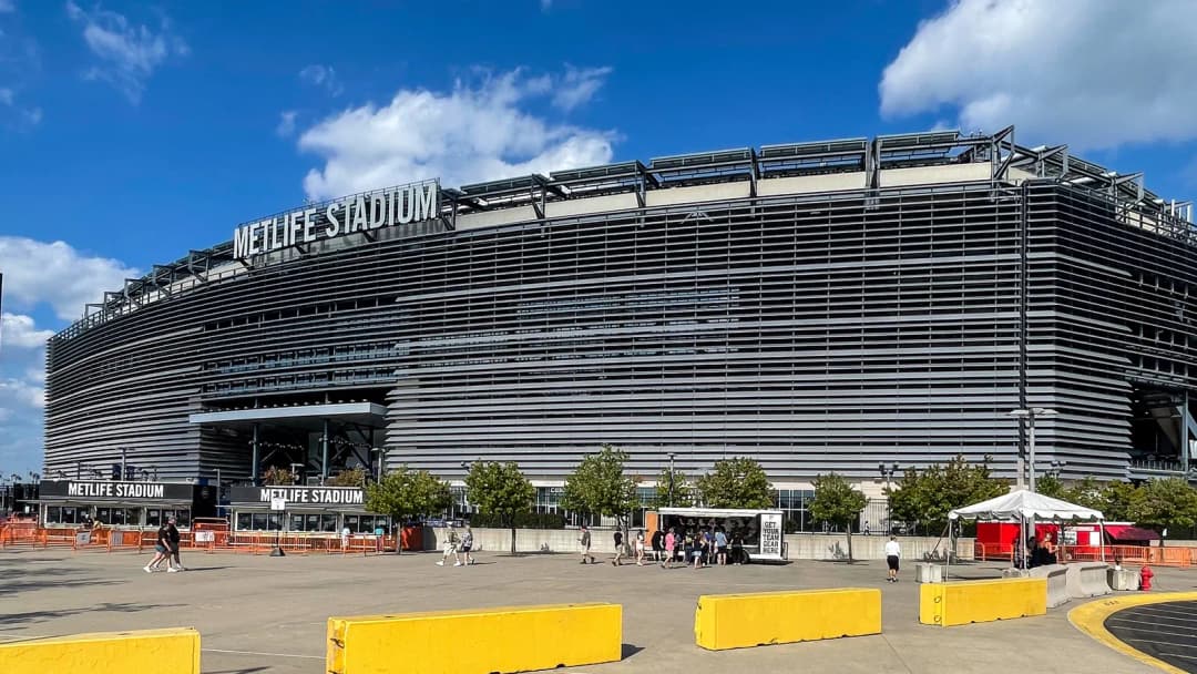 MetLife Stadium exterior in East Rutherford, New Jersey, under a blue sky with clouds.